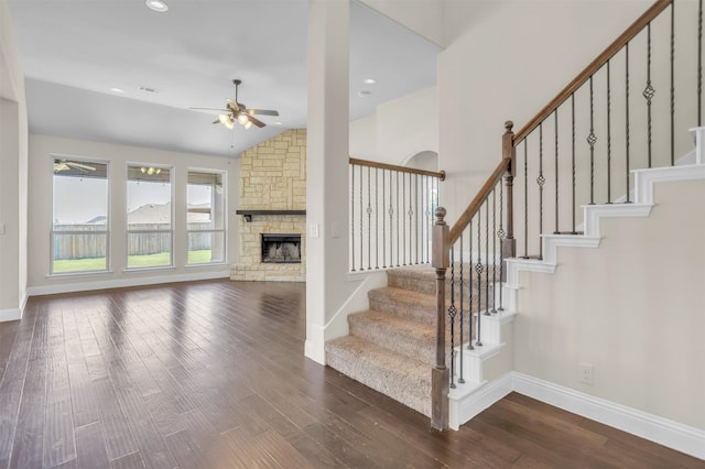 stairs featuring wood-type flooring, lofted ceiling, a fireplace, and ceiling fan