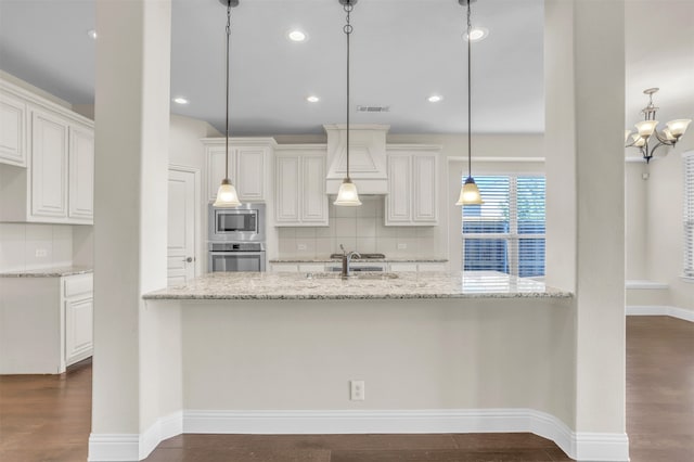 kitchen with appliances with stainless steel finishes, light stone countertops, hanging light fixtures, and white cabinets