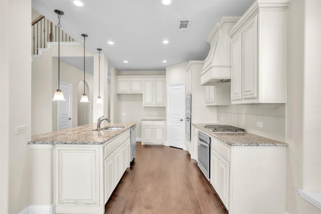 kitchen with pendant lighting, appliances with stainless steel finishes, light stone countertops, and white cabinets