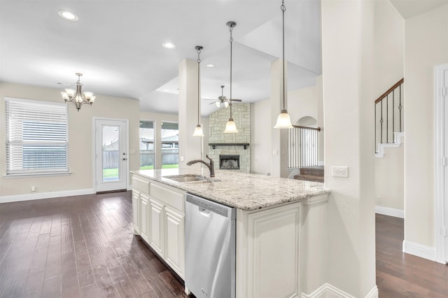 kitchen featuring ceiling fan with notable chandelier, a fireplace, sink, stainless steel dishwasher, and light stone countertops