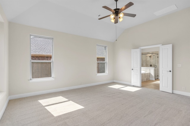 unfurnished bedroom with multiple windows, lofted ceiling, ensuite bath, and light carpet