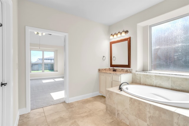 bathroom with tile patterned flooring, vanity, and a relaxing tiled tub