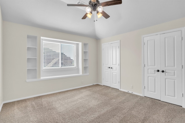 unfurnished bedroom with multiple closets, ceiling fan, carpet flooring, and vaulted ceiling