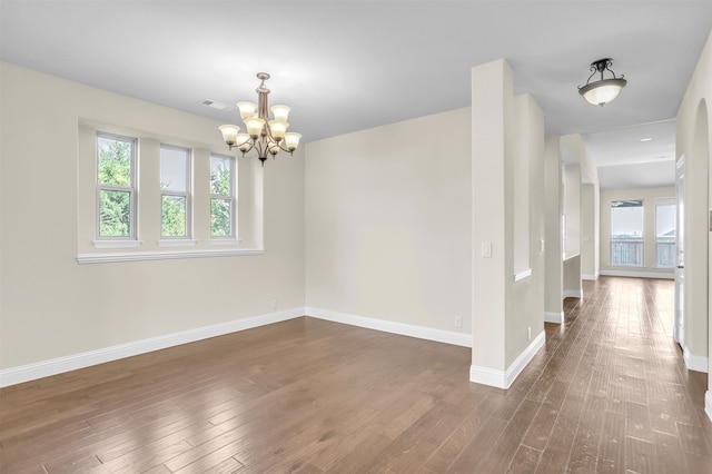 empty room with dark hardwood / wood-style floors and an inviting chandelier