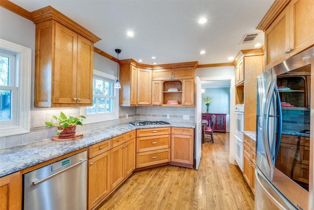 kitchen with decorative light fixtures, tasteful backsplash, light stone counters, stainless steel appliances, and light hardwood / wood-style flooring