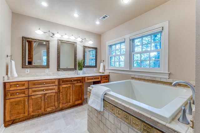 bathroom featuring vanity and tiled tub