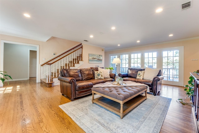 living room with light wood-type flooring and ornamental molding