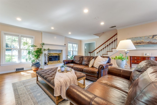 living room with crown molding, light hardwood / wood-style flooring, and plenty of natural light