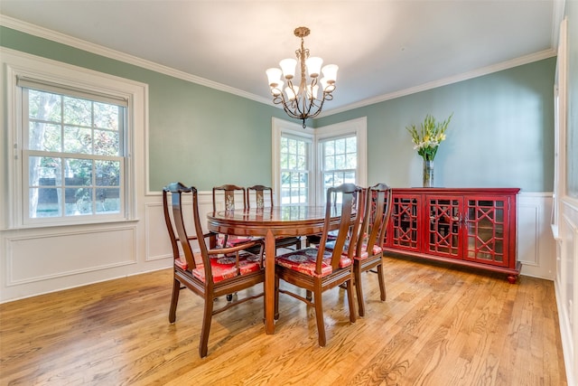 dining area featuring light hardwood / wood-style floors, ornamental molding, and a chandelier