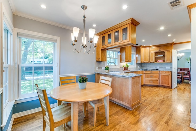 kitchen with decorative backsplash, light stone countertops, pendant lighting, and an inviting chandelier