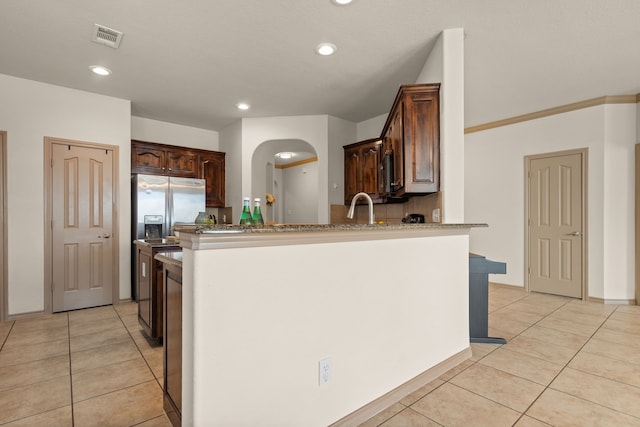 kitchen with dark brown cabinetry, light tile patterned floors, sink, kitchen peninsula, and stainless steel refrigerator with ice dispenser