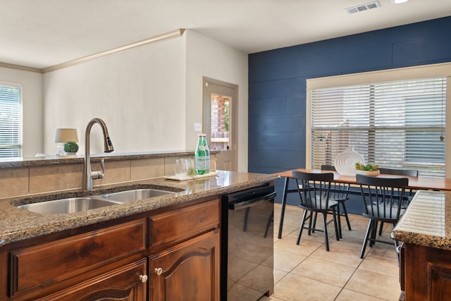 kitchen with crown molding, dark stone countertops, sink, dishwasher, and light tile patterned floors