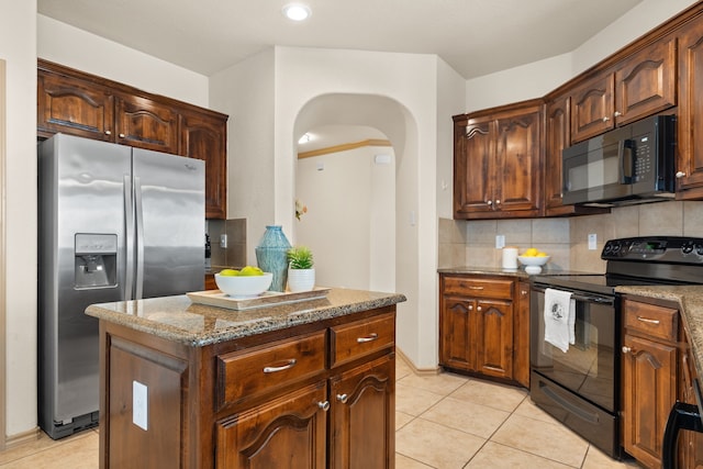 kitchen featuring stone countertops, a kitchen island, backsplash, black appliances, and light tile patterned floors