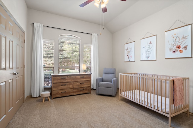 carpeted bedroom featuring a nursery area, ceiling fan, a closet, and vaulted ceiling