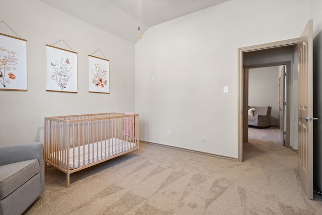 bedroom with a crib, light colored carpet, and vaulted ceiling