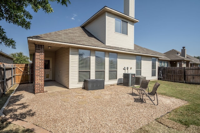 rear view of property featuring cooling unit, a lawn, and a patio area