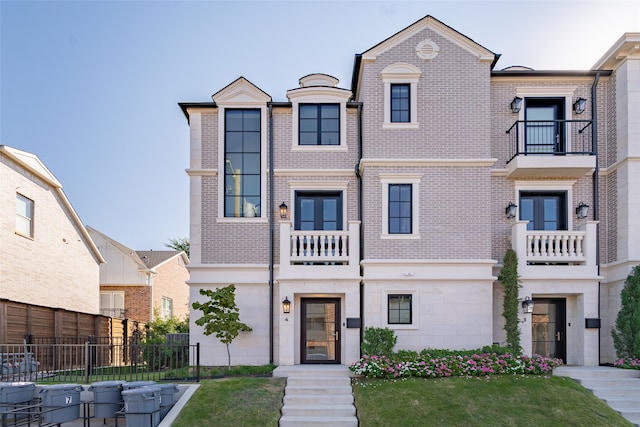 view of front of house with a balcony and a front lawn