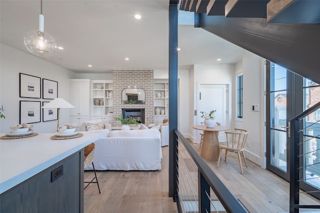 kitchen with pendant lighting, built in features, a fireplace, and light wood-type flooring