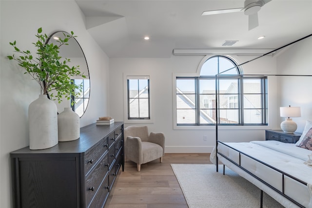 bedroom with ceiling fan, vaulted ceiling, and light hardwood / wood-style floors