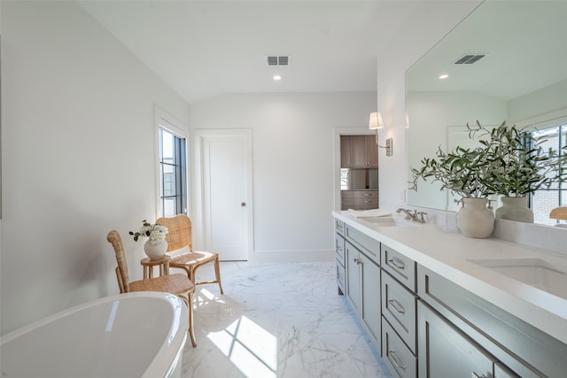 bathroom with vanity, plenty of natural light, vaulted ceiling, and a bath