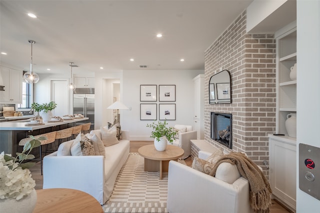 living room featuring a brick fireplace and light hardwood / wood-style flooring