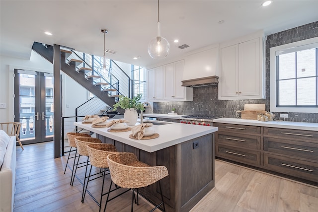 kitchen featuring a kitchen island with sink, light hardwood / wood-style floors, and white cabinets