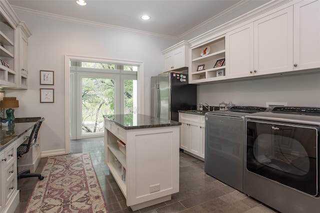 laundry area with washing machine and clothes dryer, cabinets, and ornamental molding