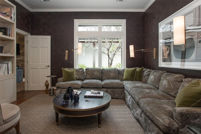 living room with built in shelves, hardwood / wood-style flooring, and ornamental molding