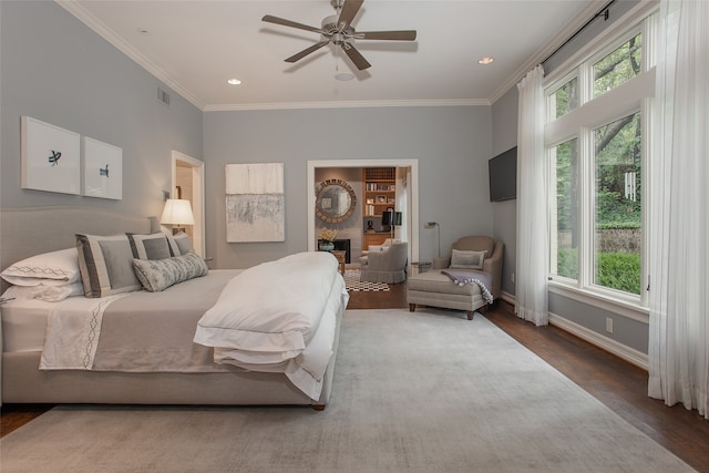 bedroom featuring ceiling fan, hardwood / wood-style flooring, multiple windows, and a large fireplace