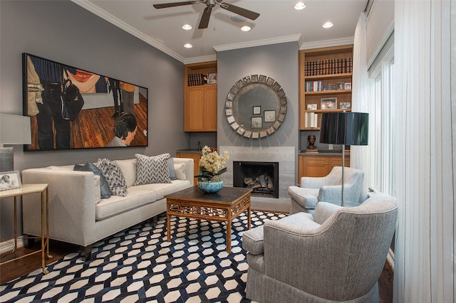 living room featuring crown molding, built in shelves, light wood-type flooring, and ceiling fan