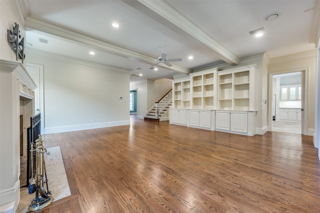 unfurnished living room with ceiling fan, hardwood / wood-style flooring, crown molding, a barn door, and beam ceiling