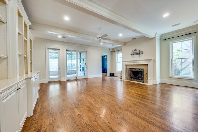 unfurnished living room featuring ornamental molding, beamed ceiling, plenty of natural light, and hardwood / wood-style floors