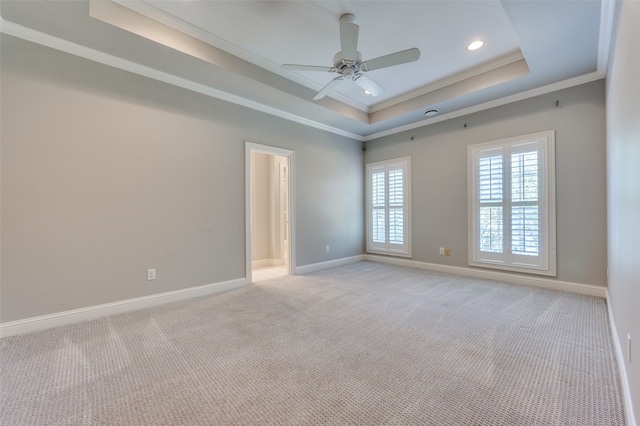 carpeted empty room with ornamental molding, a tray ceiling, and ceiling fan