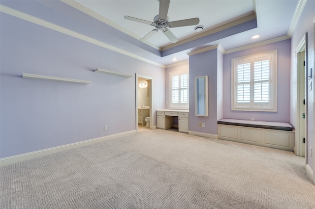 unfurnished bedroom featuring ceiling fan, ornamental molding, a tray ceiling, light carpet, and ensuite bath