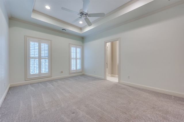 unfurnished room featuring ceiling fan, crown molding, a tray ceiling, and light colored carpet