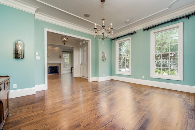 unfurnished dining area with dark wood-type flooring, ornamental molding, and an inviting chandelier