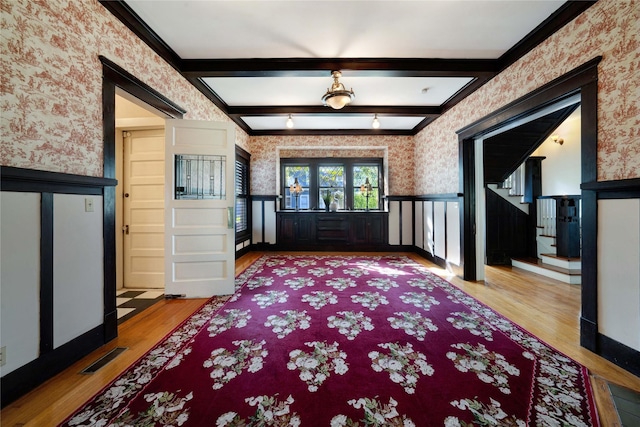 entryway featuring wallpapered walls, visible vents, wainscoting, beamed ceiling, and wood finished floors