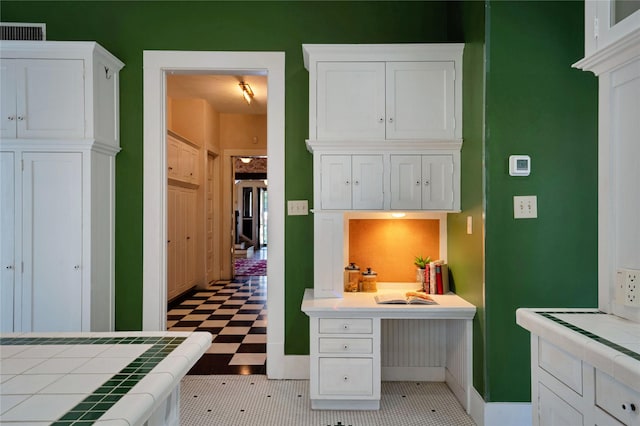 kitchen featuring tile counters, white cabinetry, and visible vents