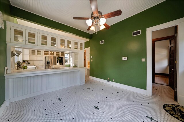 kitchen with tile countertops, a center island, black appliances, ceiling fan, and white cabinetry