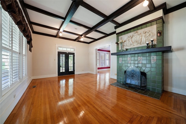 unfurnished living room with coffered ceiling, wood finished floors, baseboards, french doors, and beam ceiling