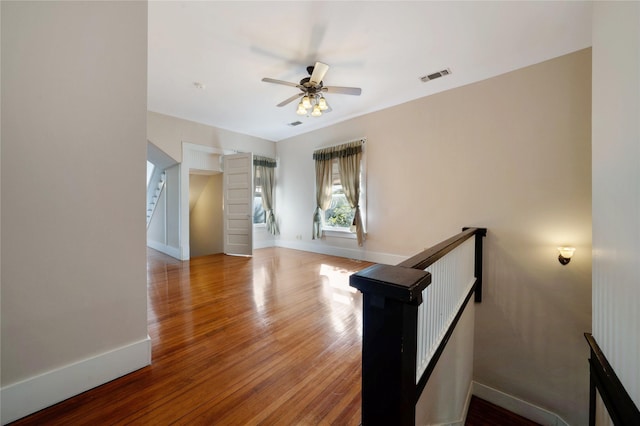 spare room featuring a ceiling fan, baseboards, visible vents, and wood finished floors