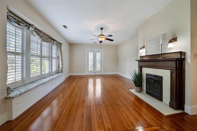 unfurnished living room with light wood-style floors, baseboards, visible vents, and a fireplace with flush hearth