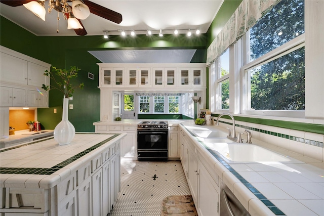 kitchen with a peninsula, black range with electric stovetop, white cabinets, tile counters, and glass insert cabinets