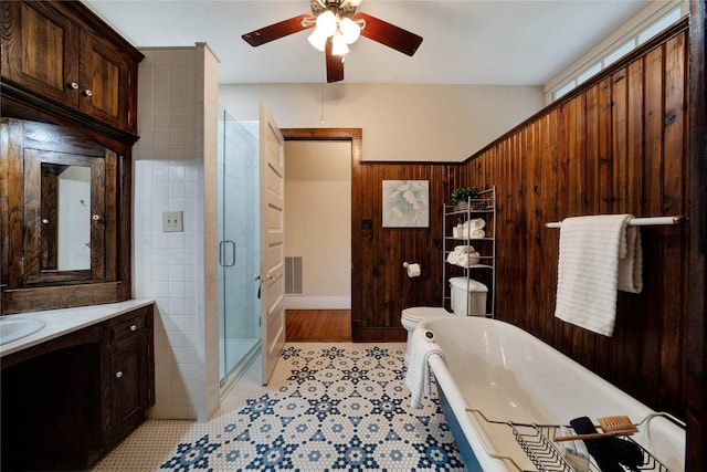 bathroom featuring vanity, a shower with door, ceiling fan, wooden walls, and toilet