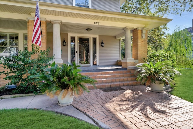 entrance to property with brick siding and a porch