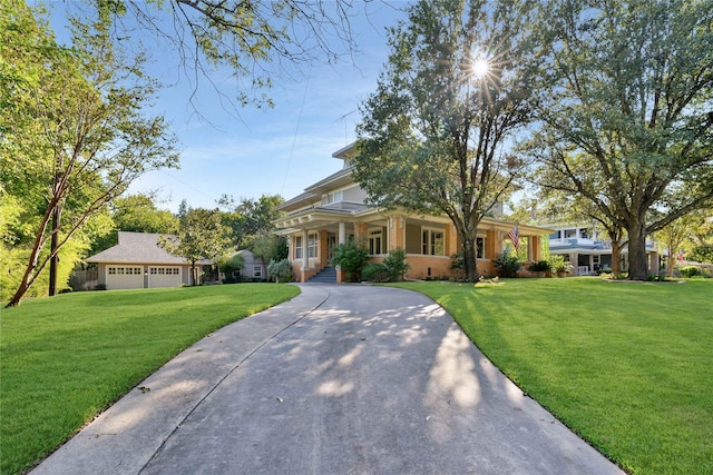 view of front of home featuring covered porch, a front yard, a detached garage, and an outbuilding