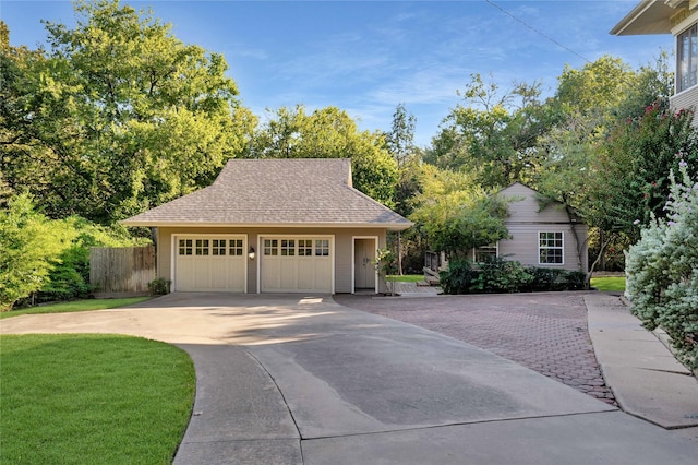 view of front of home featuring a shingled roof, a detached garage, fence, and an outdoor structure