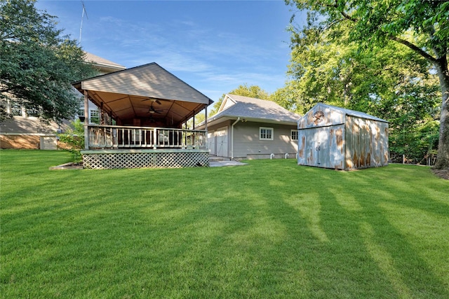 rear view of property featuring a lawn, ceiling fan, a shed, an outdoor structure, and a wooden deck