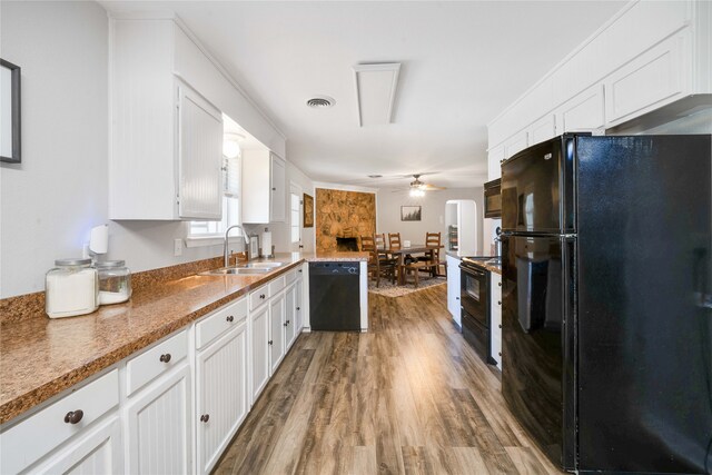 kitchen featuring kitchen peninsula, white cabinets, black appliances, and hardwood / wood-style floors