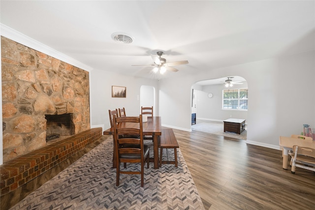 dining room with a fireplace, ceiling fan, dark hardwood / wood-style floors, and crown molding